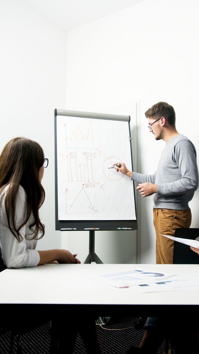 about-us A businessperson giving a presentation with charts in a modern office environment.