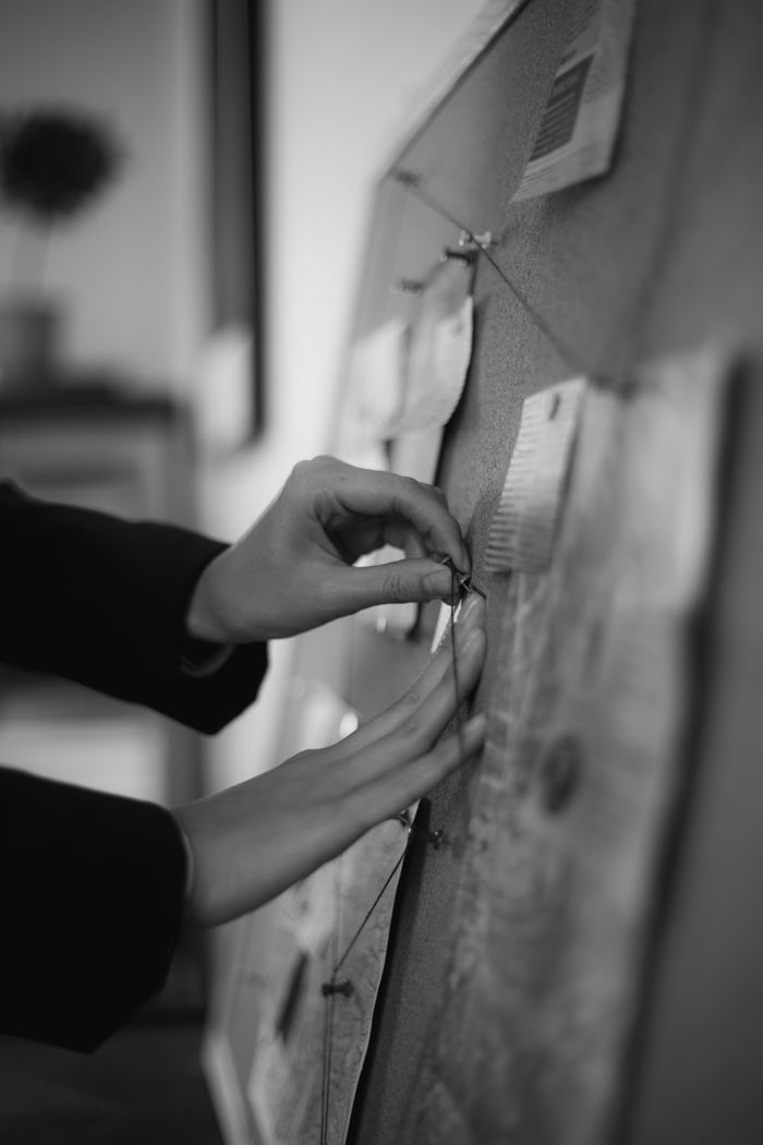 The Art of Drawing Readers In: Your attractive post title goes here Close-up of hands pinning notes on a cork board in black and white.